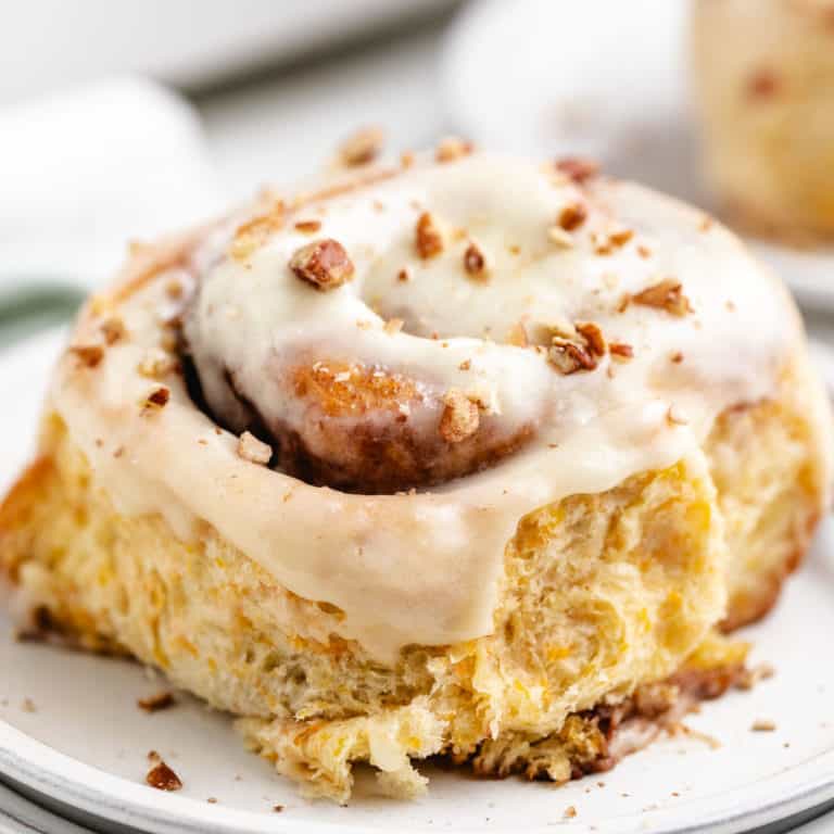 Close up view of a carrot cake cinnamon roll on a plate.