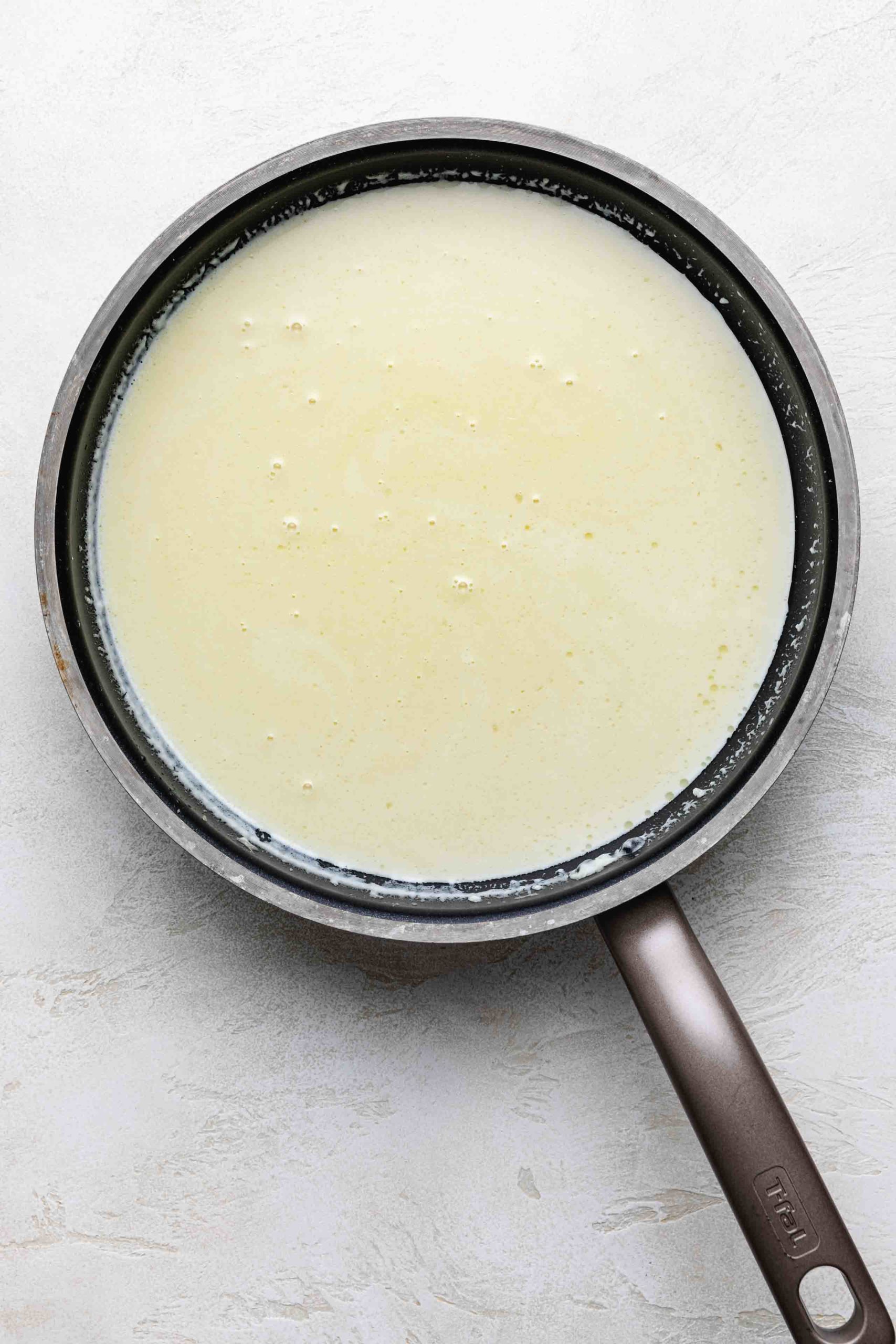 Heavy cream and milk heating in a pan.