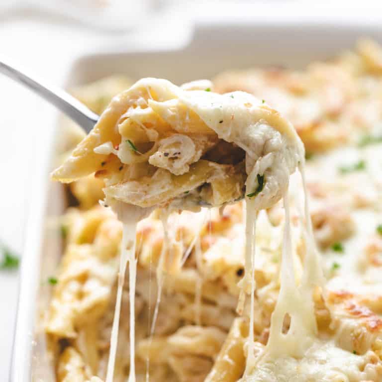 Cheesy chicken alfredo bake being scooped from a pan.