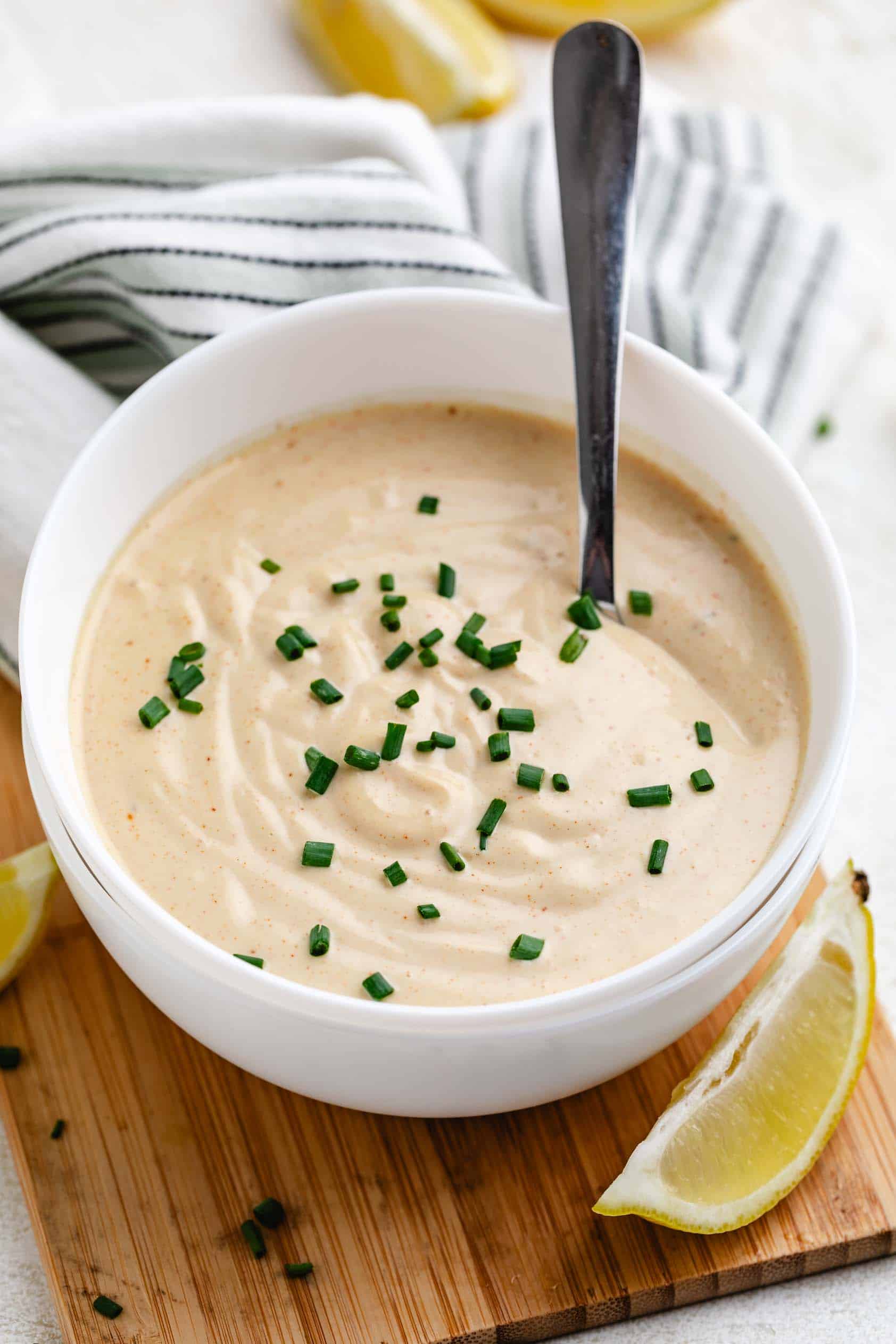 Lemons next to a bowl of crab cake sauce.