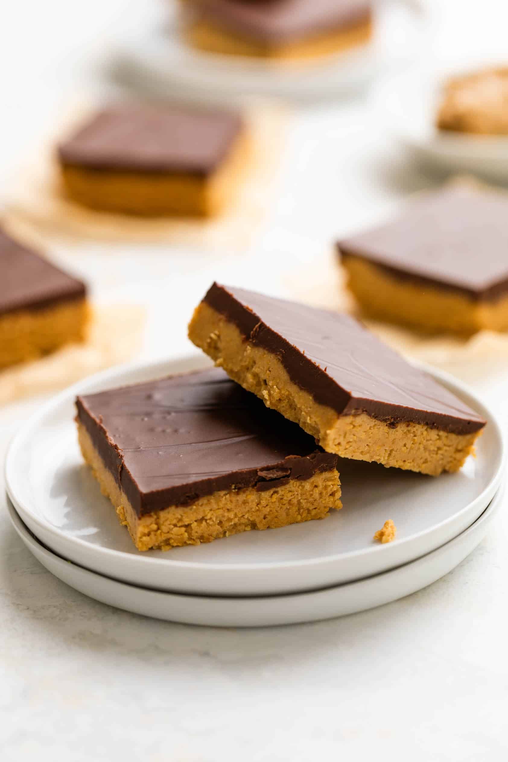 Two peanut butter chocolate bars on a stack of plates.