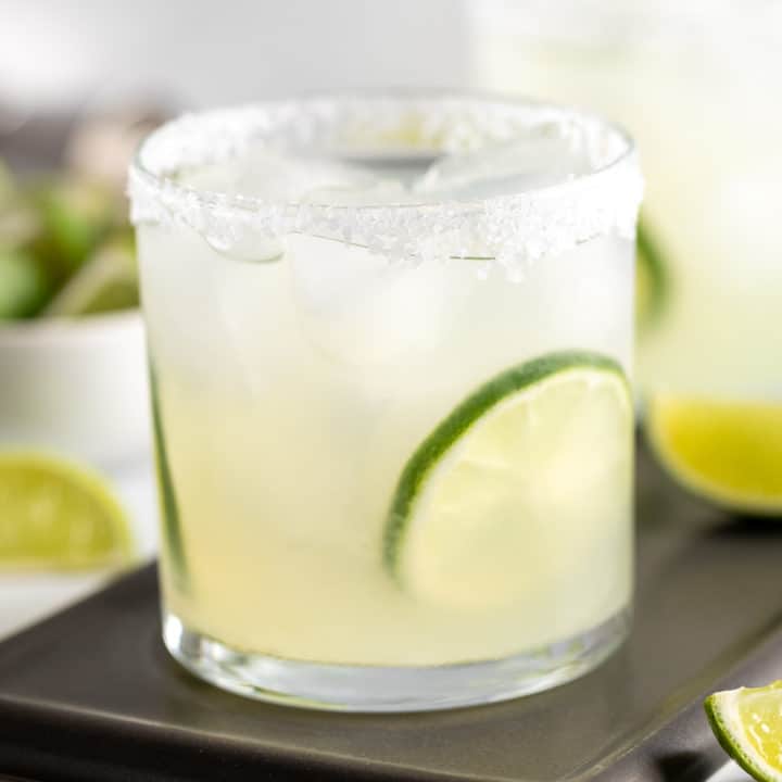 Margarita in a glass with ice and lime wheels.