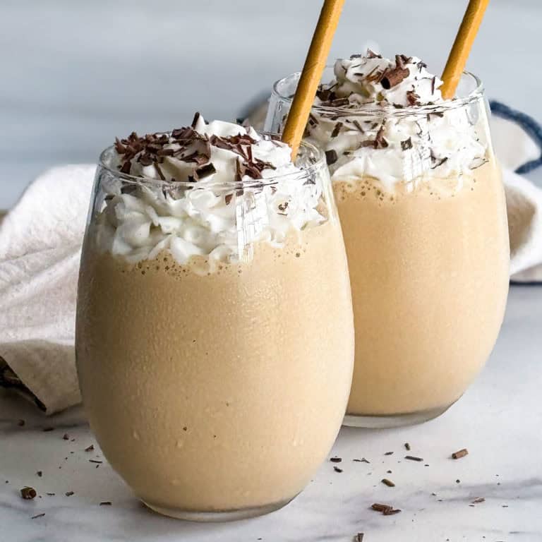 Two boozy milkshakes in glasses with whipped cream.