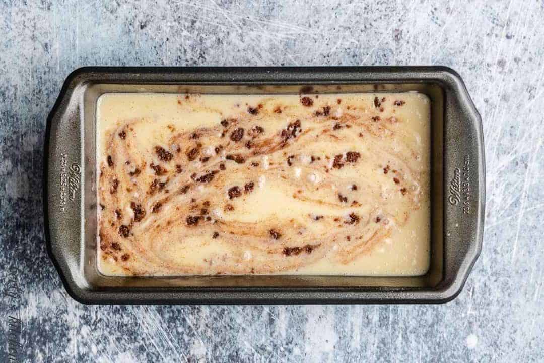 The batter and cinnamon mixture combined in a loaf pan.