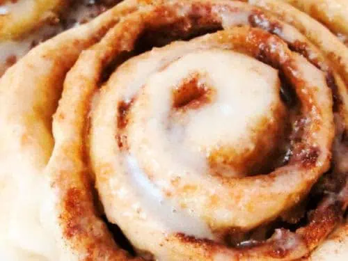 Close-up view of a freshly baked pastry with a swirl pattern, topped with a light layer of icing.