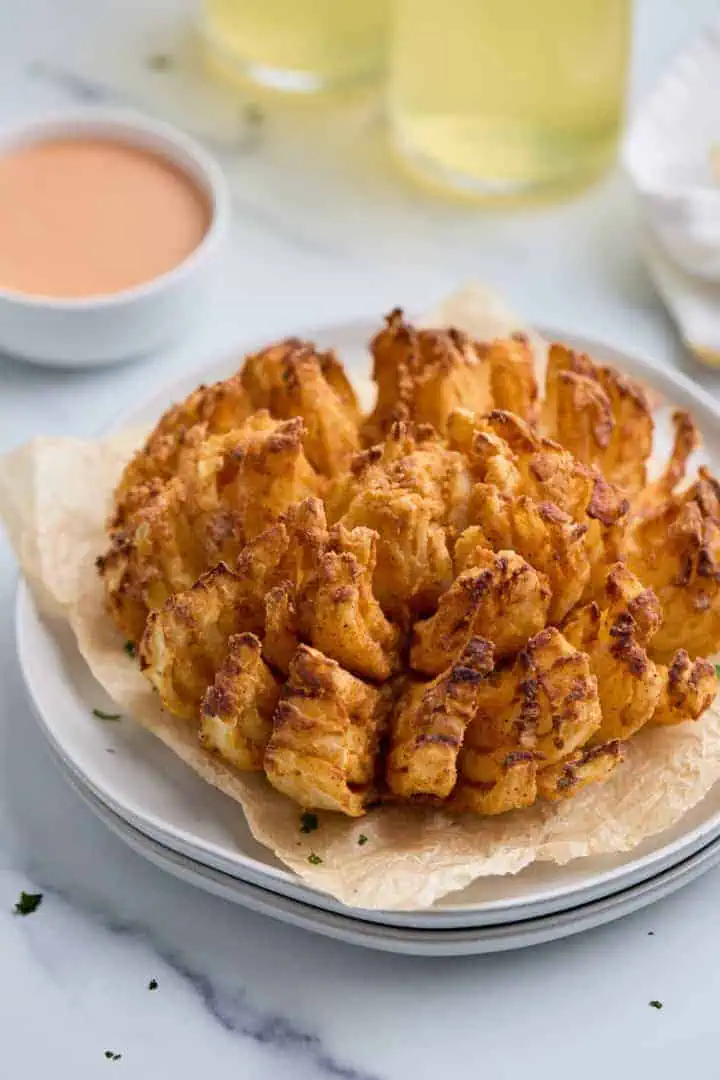 Air fryer blooming onion served on a white plate, garnished with parsley.