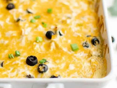 Close up of a green chile chicken casserole in a white baking dish.