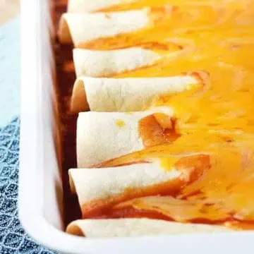 Cheesy chorizo enchiladas in a white pan.