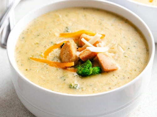 Close up view of a white bowl filled with broccoli cheddar soup.