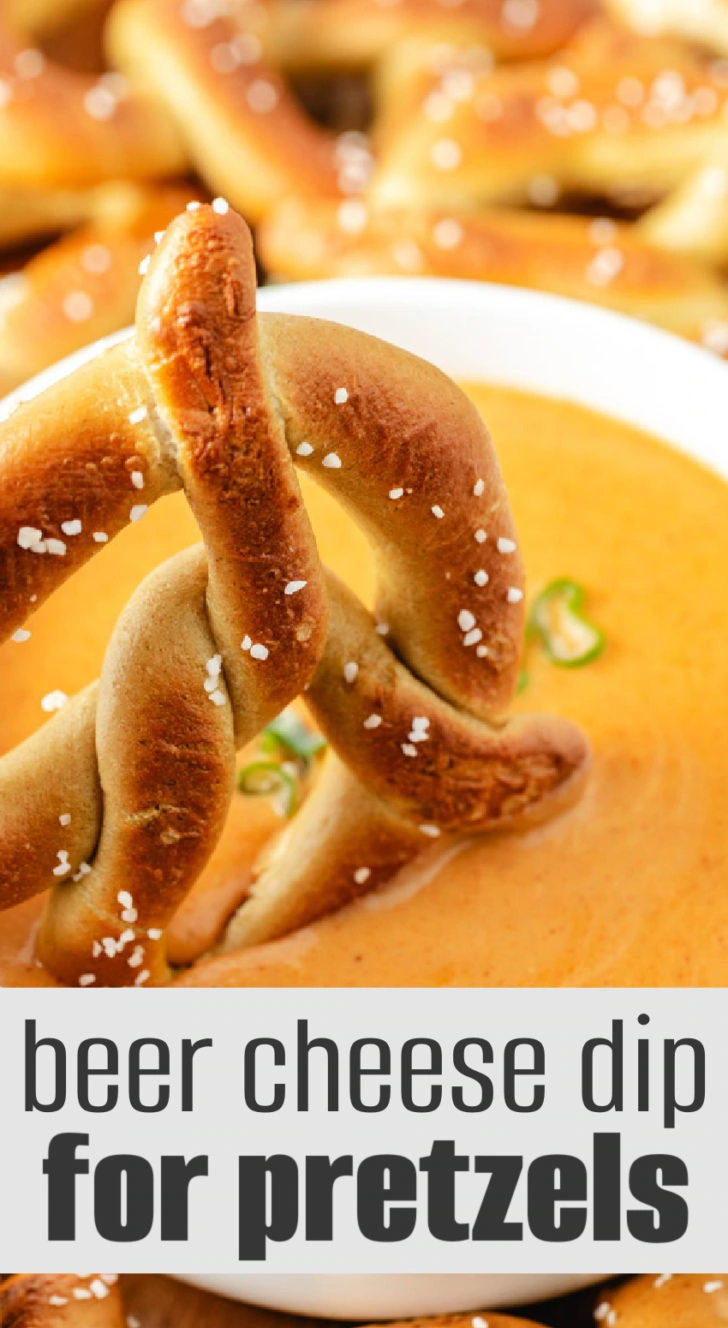 Close-up of a soft pretzel dipped into a bowl of warm beer cheese sauce.