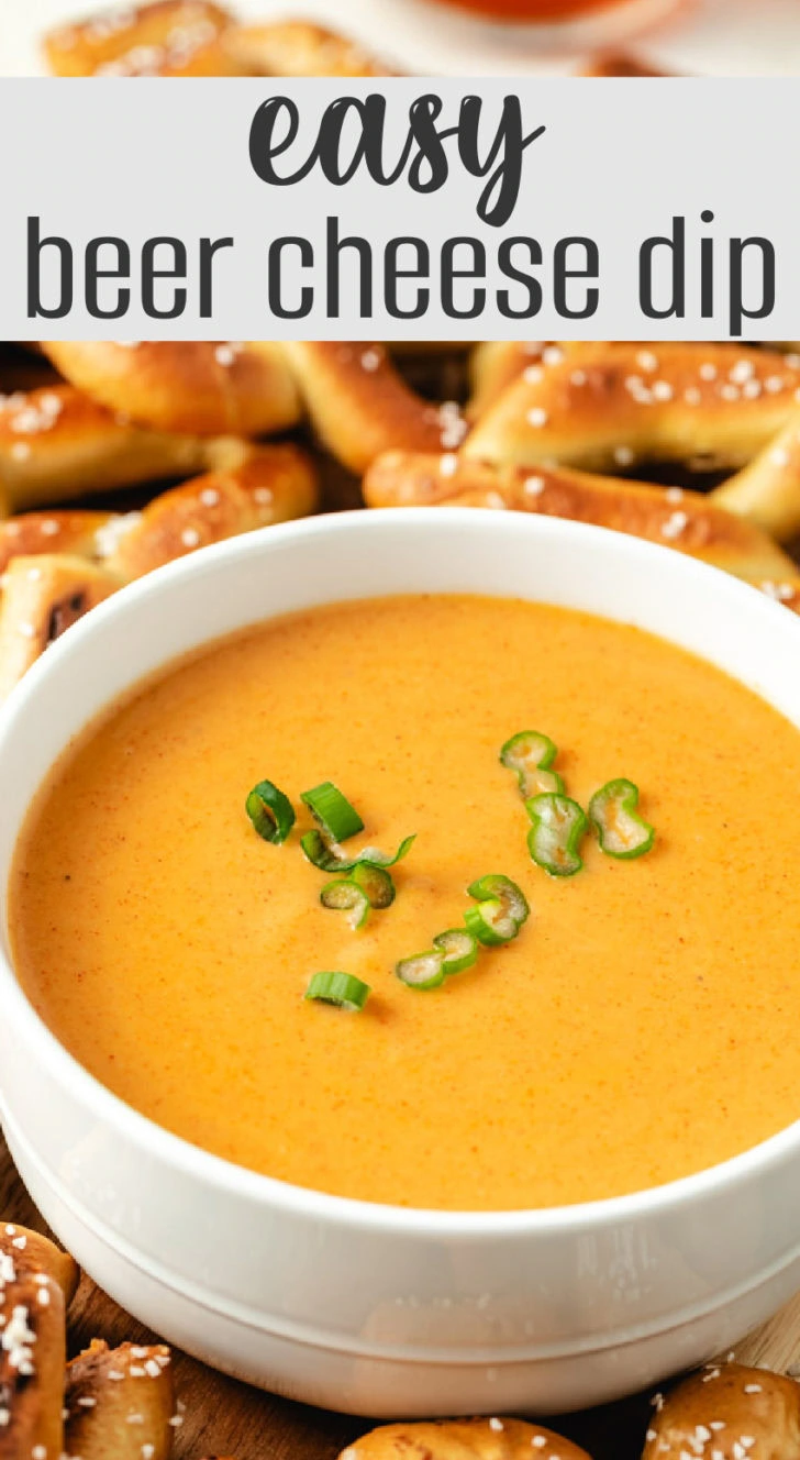 A close-up of beer cheese dip with a golden soft pretzel being dipped in.