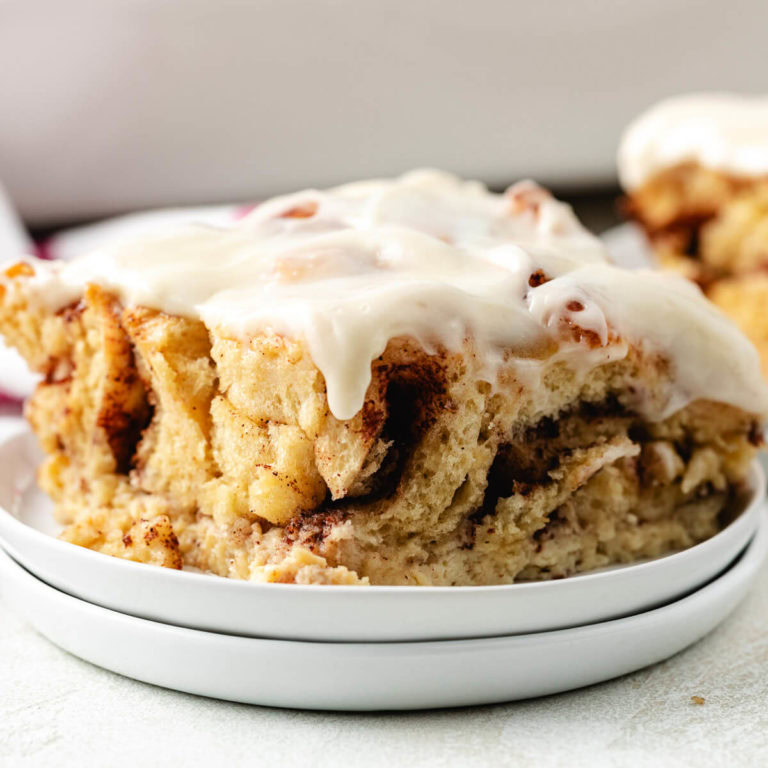 Close up view of a slice of cinnamon roll french toast bake on a stack of plates.