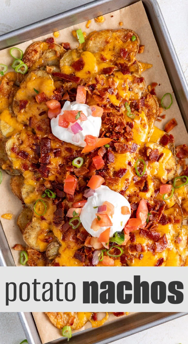 Overhead shot of a tray of baked potato nachos with bacon, cheese, and fresh toppings.
