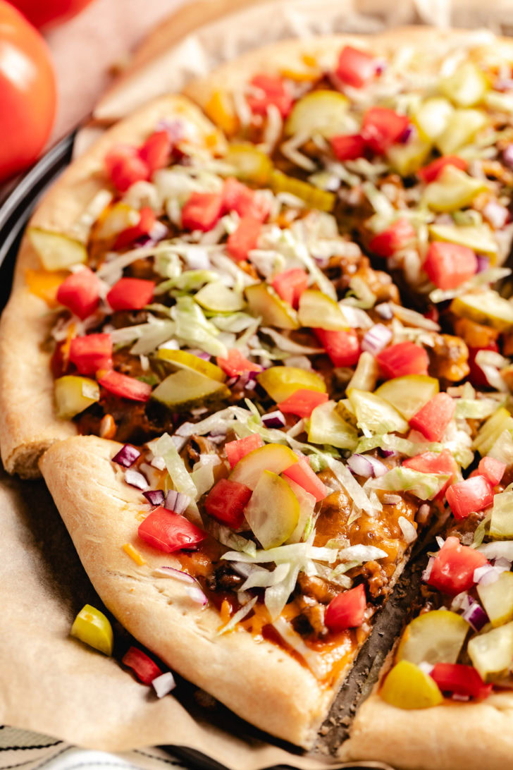 Cheeseburger Pizza A pizza with toppings on a pan on a table.