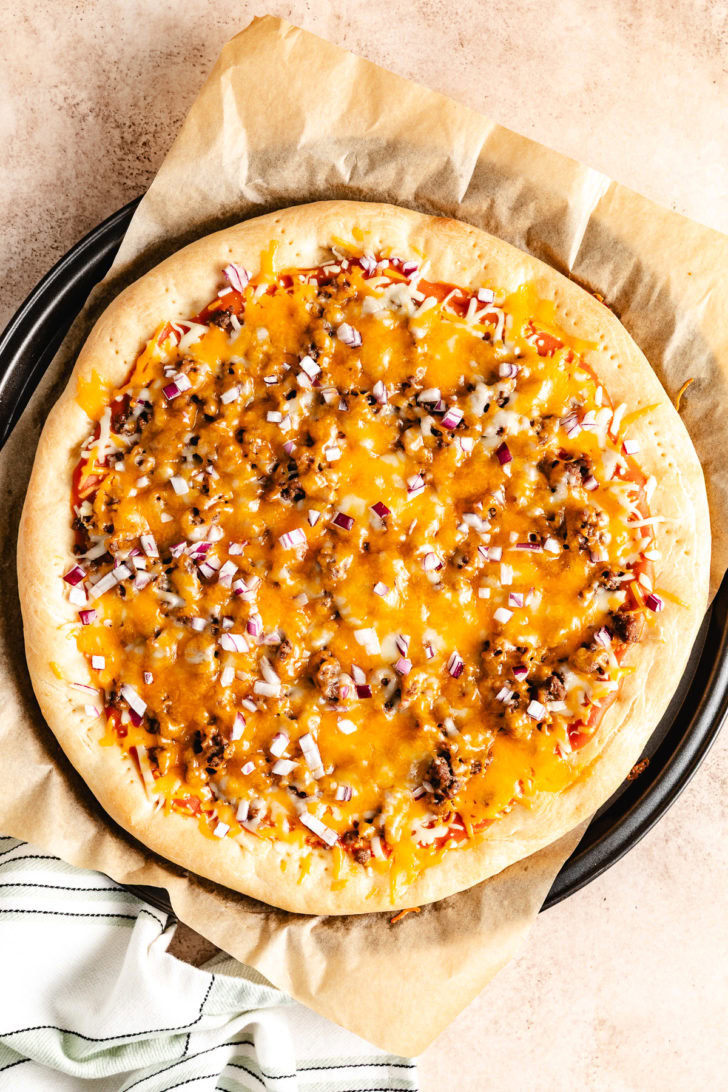 A pizza on a tray with cheese and onions.