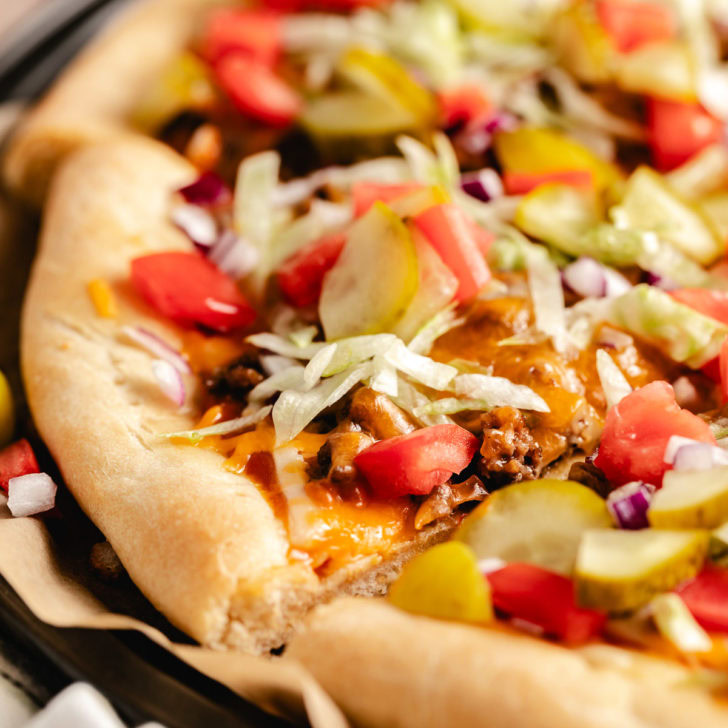 Close up view of a cheeseburger pizza on a pan.
