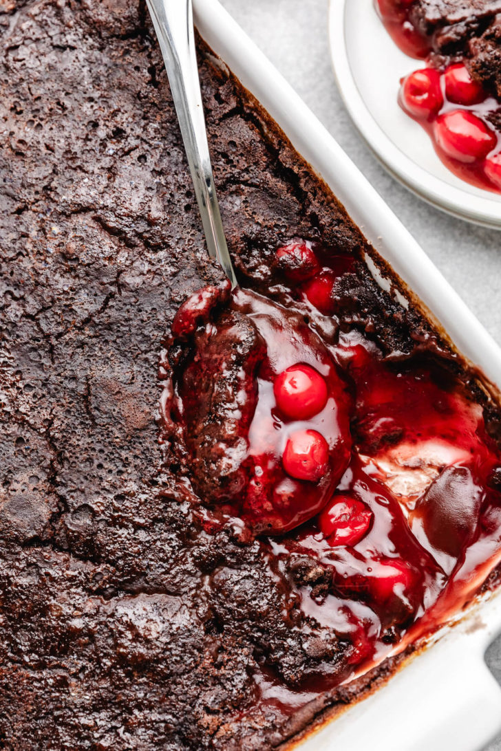 Spoon scooping cherry cola dump cake.