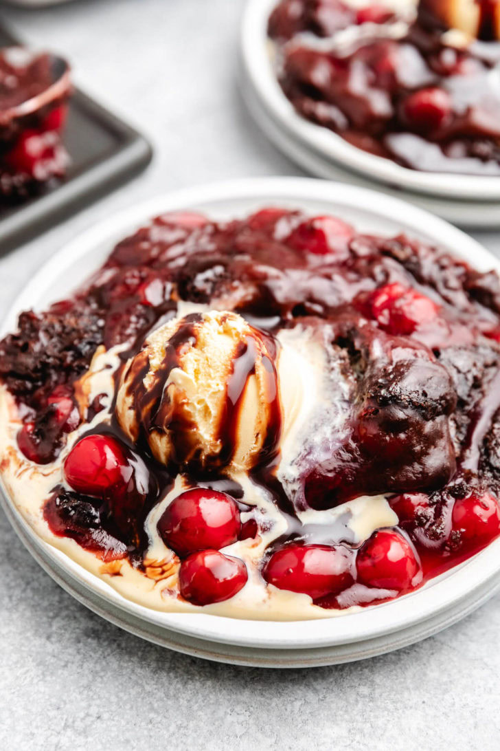 Side view of chocolate cherry cake topped with ice cream.
