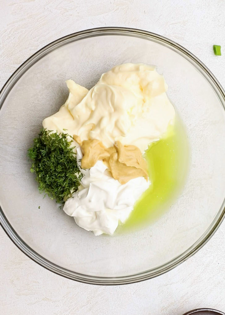 A bowl of mayonnaise, sour cream, and herbs.