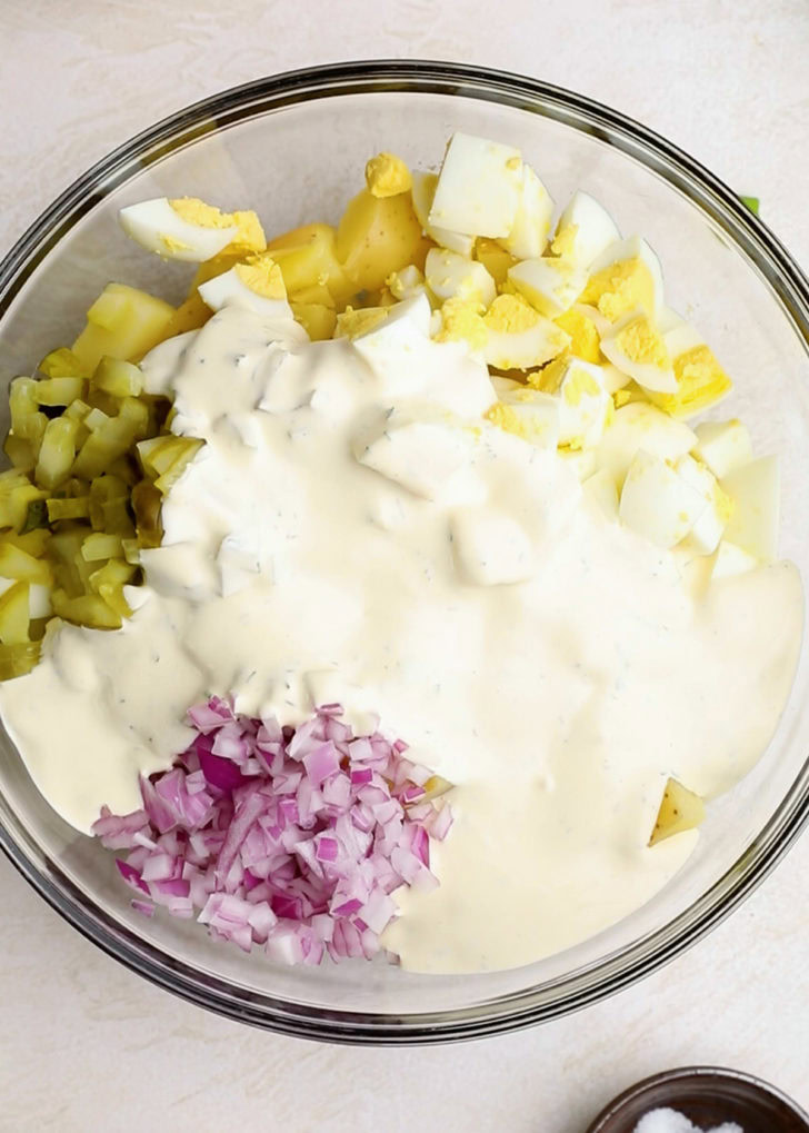 A bowl of ingredients including onions, peppers, and eggs.
