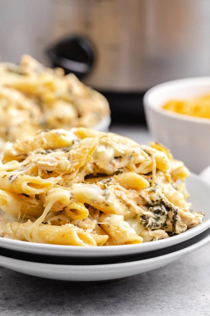 Blue plate filled with crock pot spinach artichoke chicken pasta.