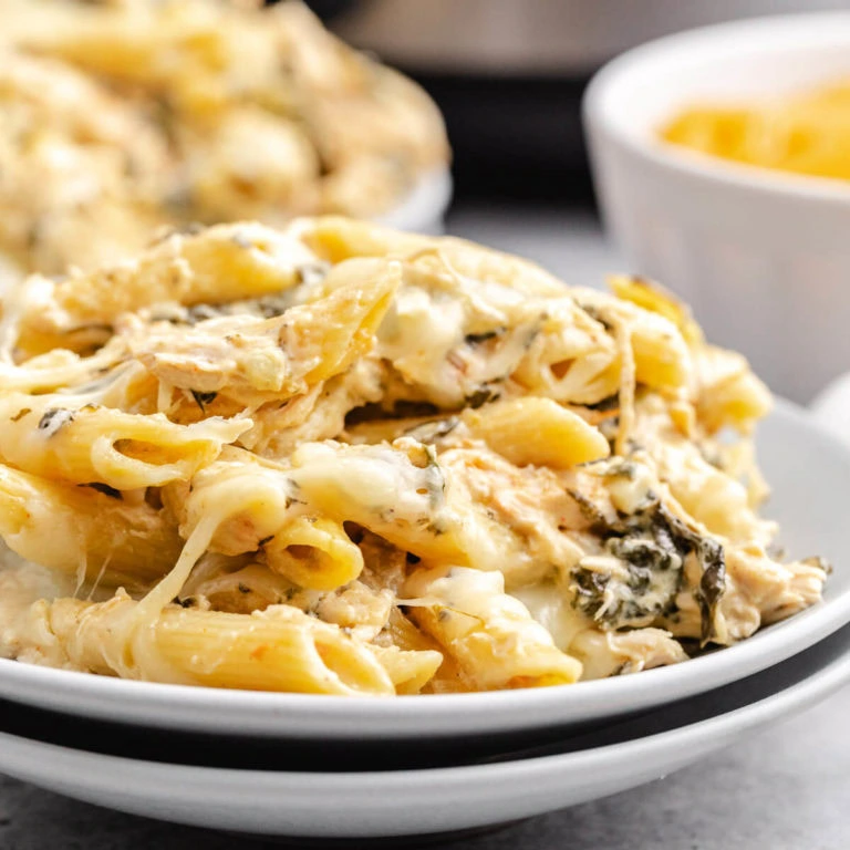 Close up view of slow cooker spinach artichoke chicken pasta on a plate.