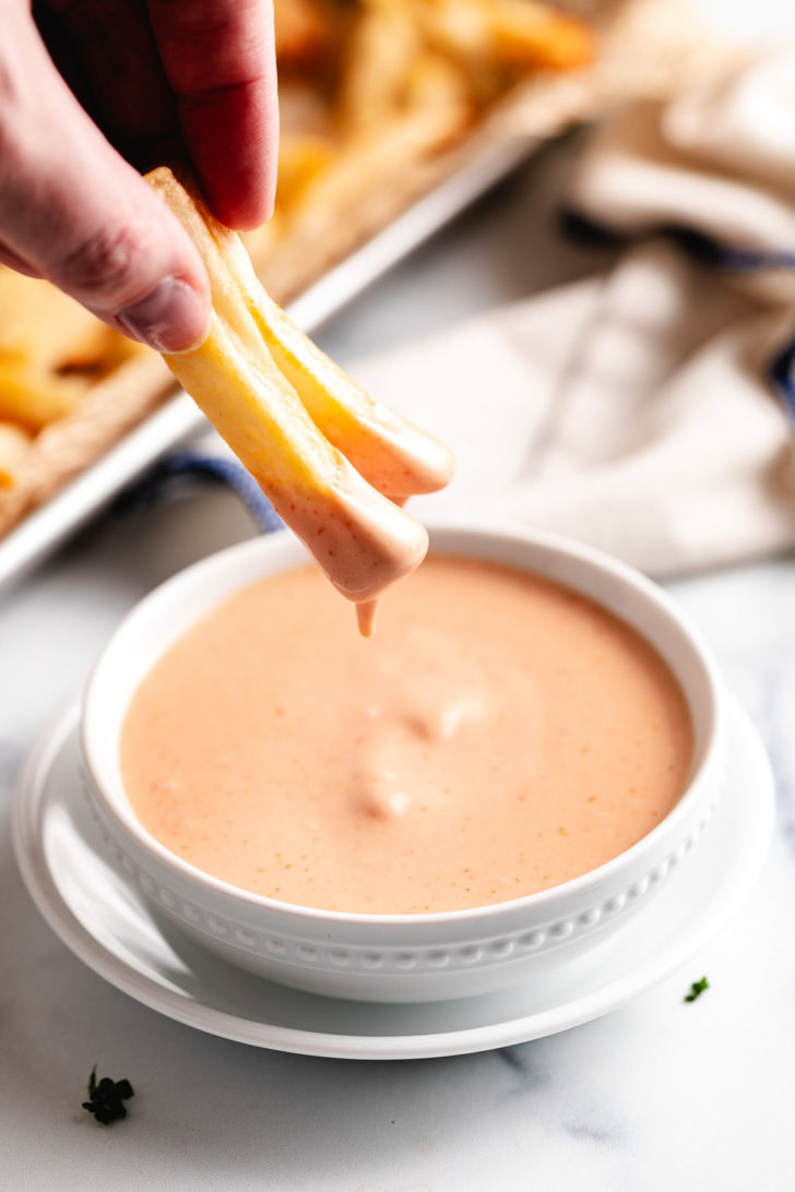 Two fries being dipped into fry sauce.