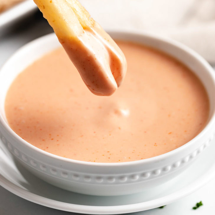French fries being dipped into sauce.