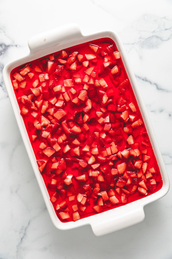 Strawberry gelatin poured over cream cheese and strawberries.