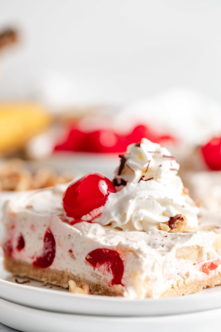 Banana split dessert with whipped cream and cherries.
