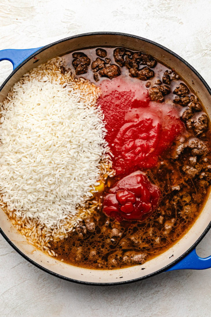 Rice, tomato sauce, and broth added to seasoned ground beef.