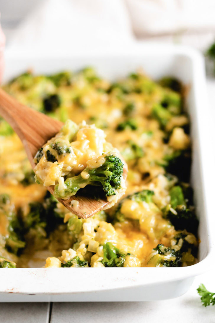 Spoon holding broccoli cheese rice casserole.