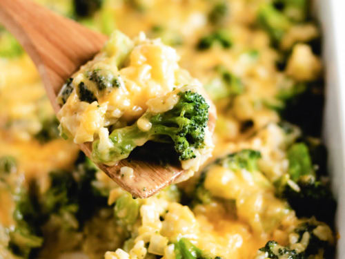 Wooden spoon scooping broccoli cheese rice casserole.
