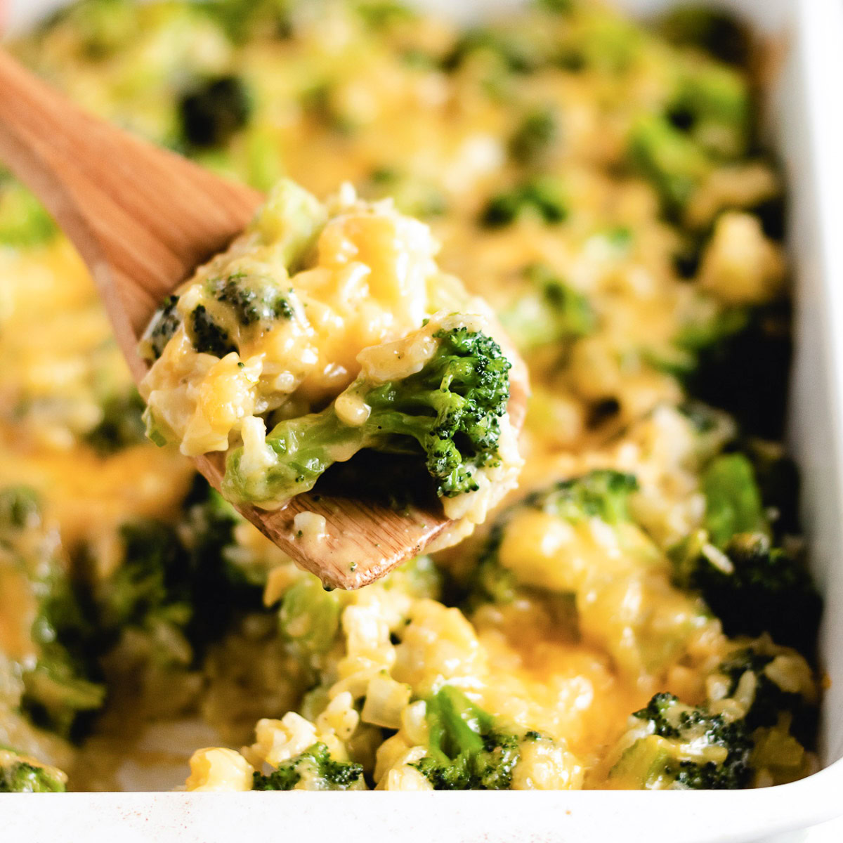 Wooden spoon scooping broccoli cheese rice casserole.