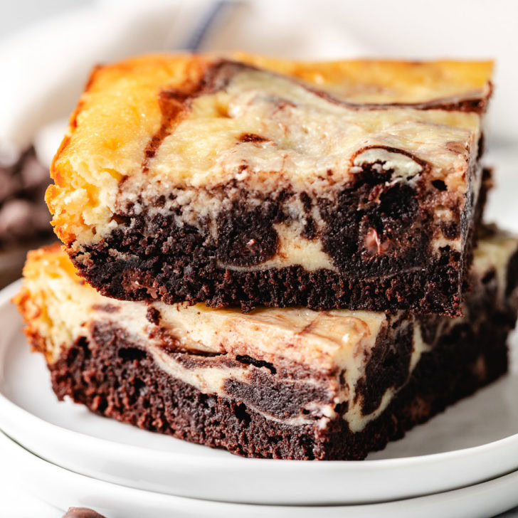 Close up view of cheesecake swirl brownies on two plates.