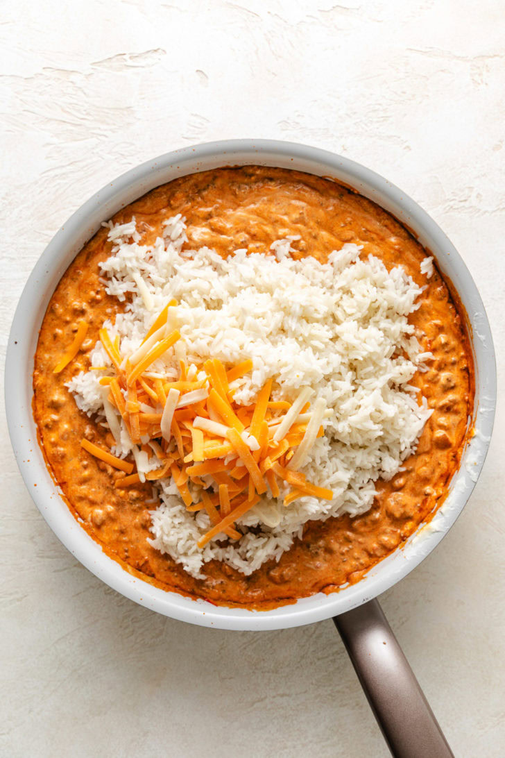 Rice and cheese added to a skillet.