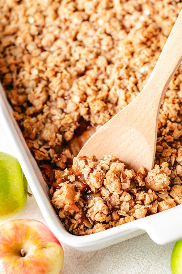 Spoon dipping in a pan of fruit crisip.