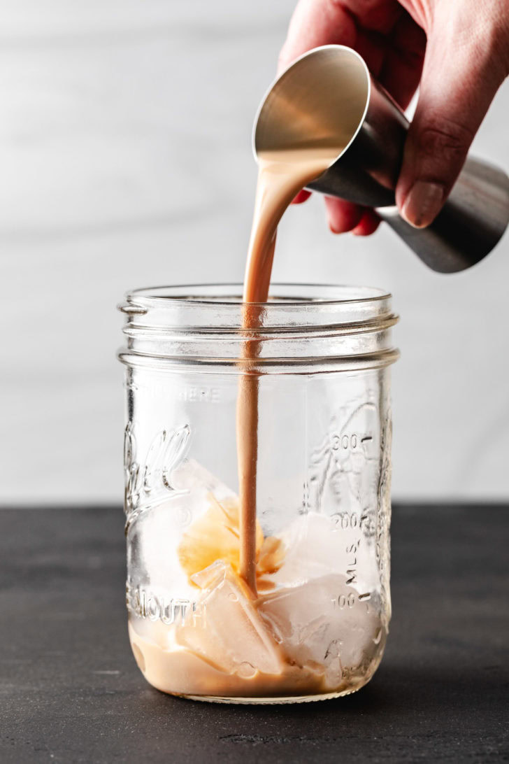 Irish cream liqueur being poured into a jar.