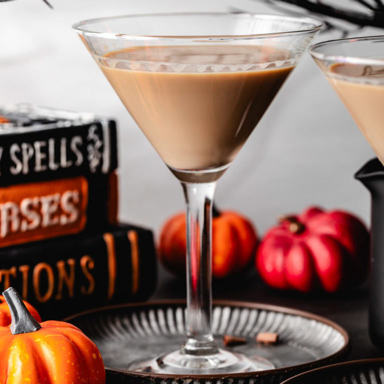 Black cat drink next to halloween decorations.