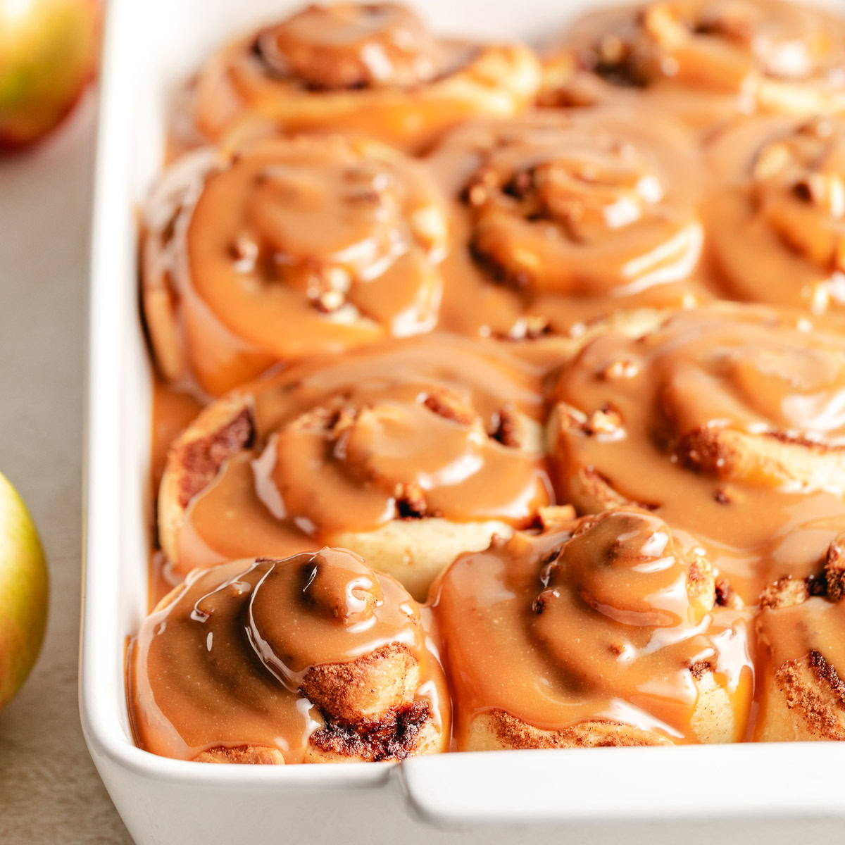 Close up view of caramel apple cinnamon rolls in a pan.