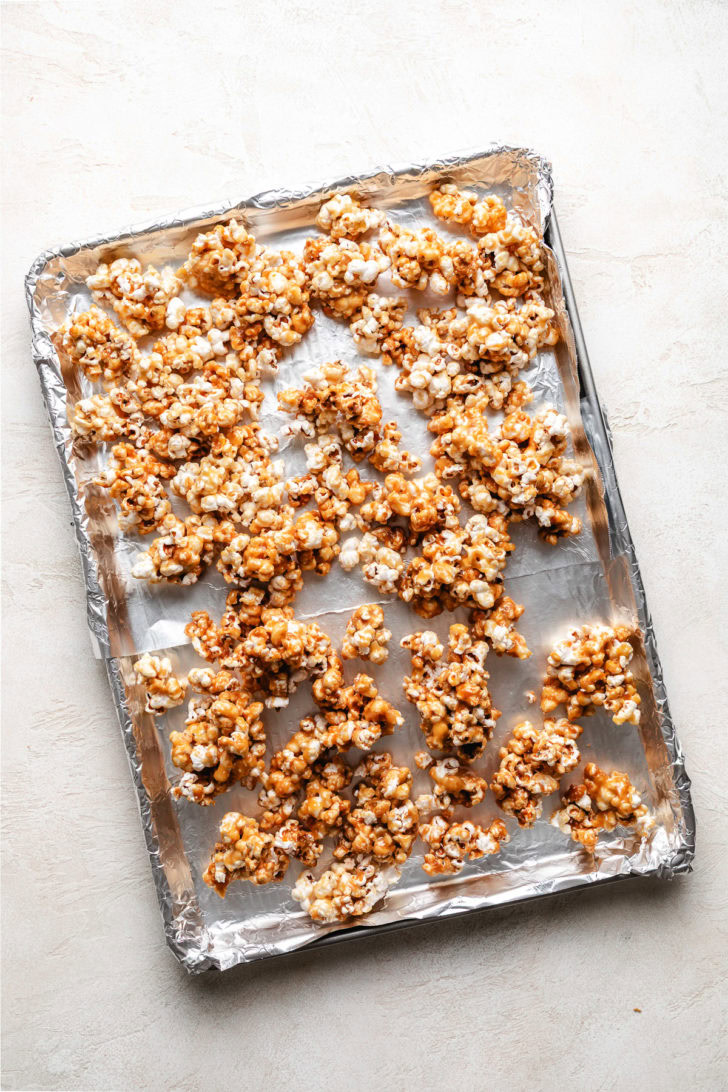 Caramel covered popcorn on a sheet pan.