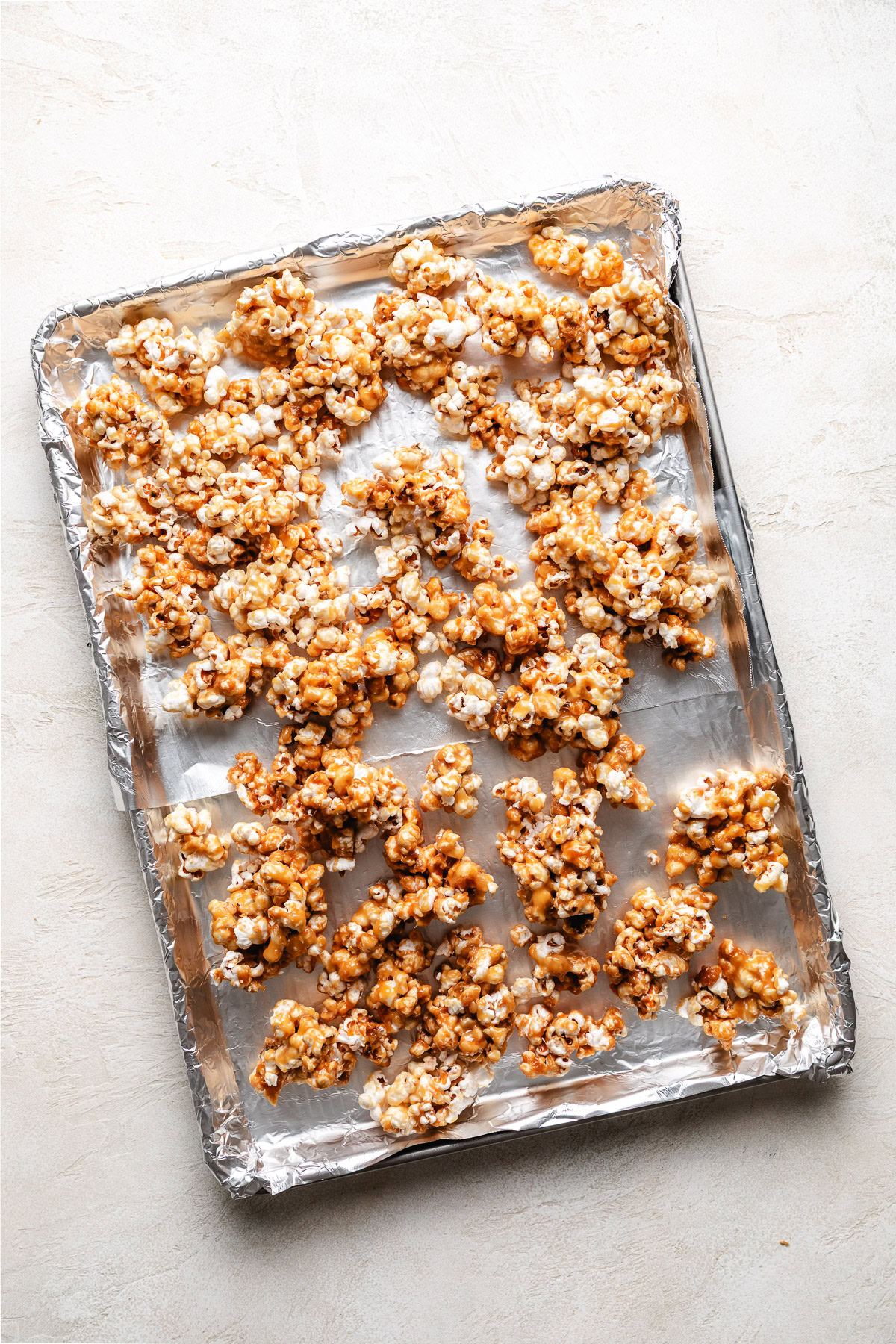 Caramel covered popcorn on a sheet pan.