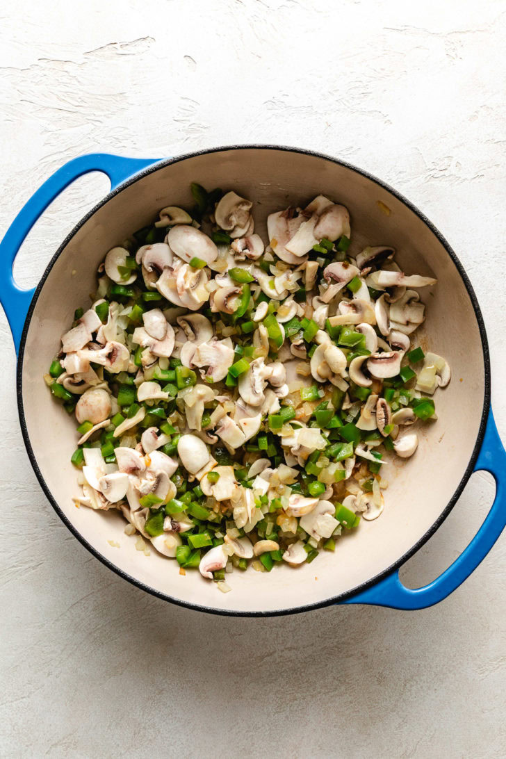 Mushrooms, onions, and peppers in a pan.
