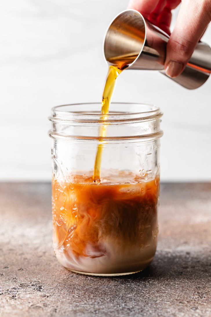 Pumpkin spice coffee syrup being poured into a jar.