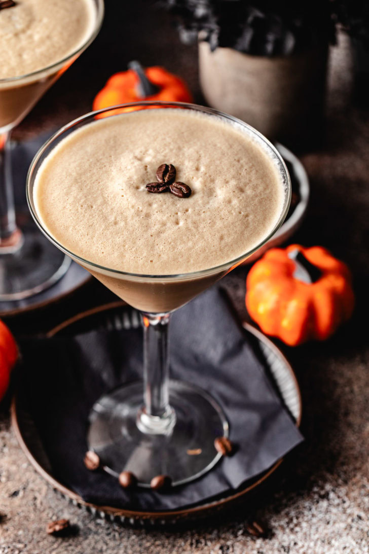 Pumpkin spice espresso martini next to a pumpkin.