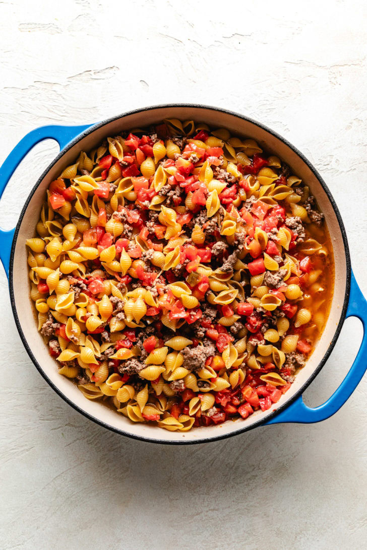 Rotel, ground beef, and noodles cooking in a pan.