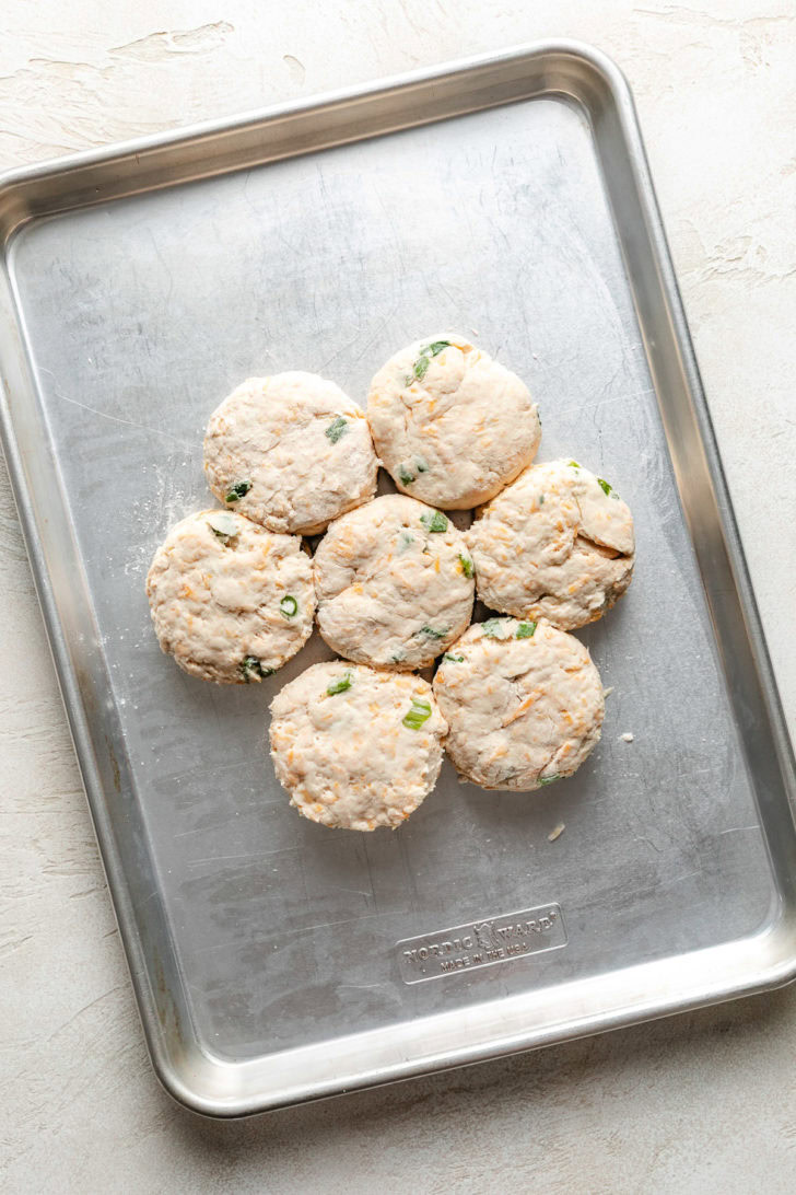 Easy Cheddar Scallion Biscuits Unbaked biscuits on a baking sheet.
