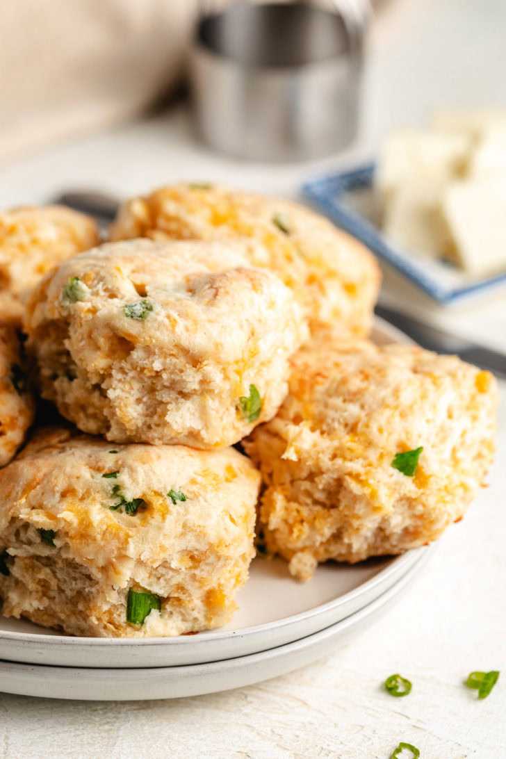 Easy Cheddar Scallion Biscuits Cheese biscuits on a stack of plates.