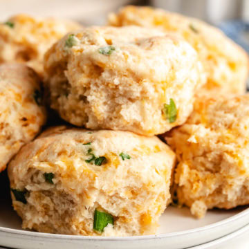 Easy Cheddar Scallion Biscuits Close up view of cheddar scallion biscuits on a plate.