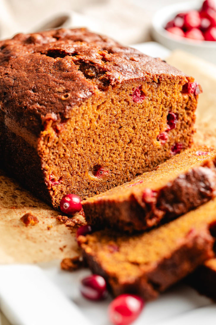 Loaf of pumpkin cranberry bread on parchment.